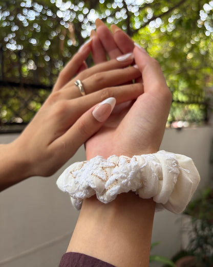 Close-up of hands with a white scrunchie on a blurred natural background