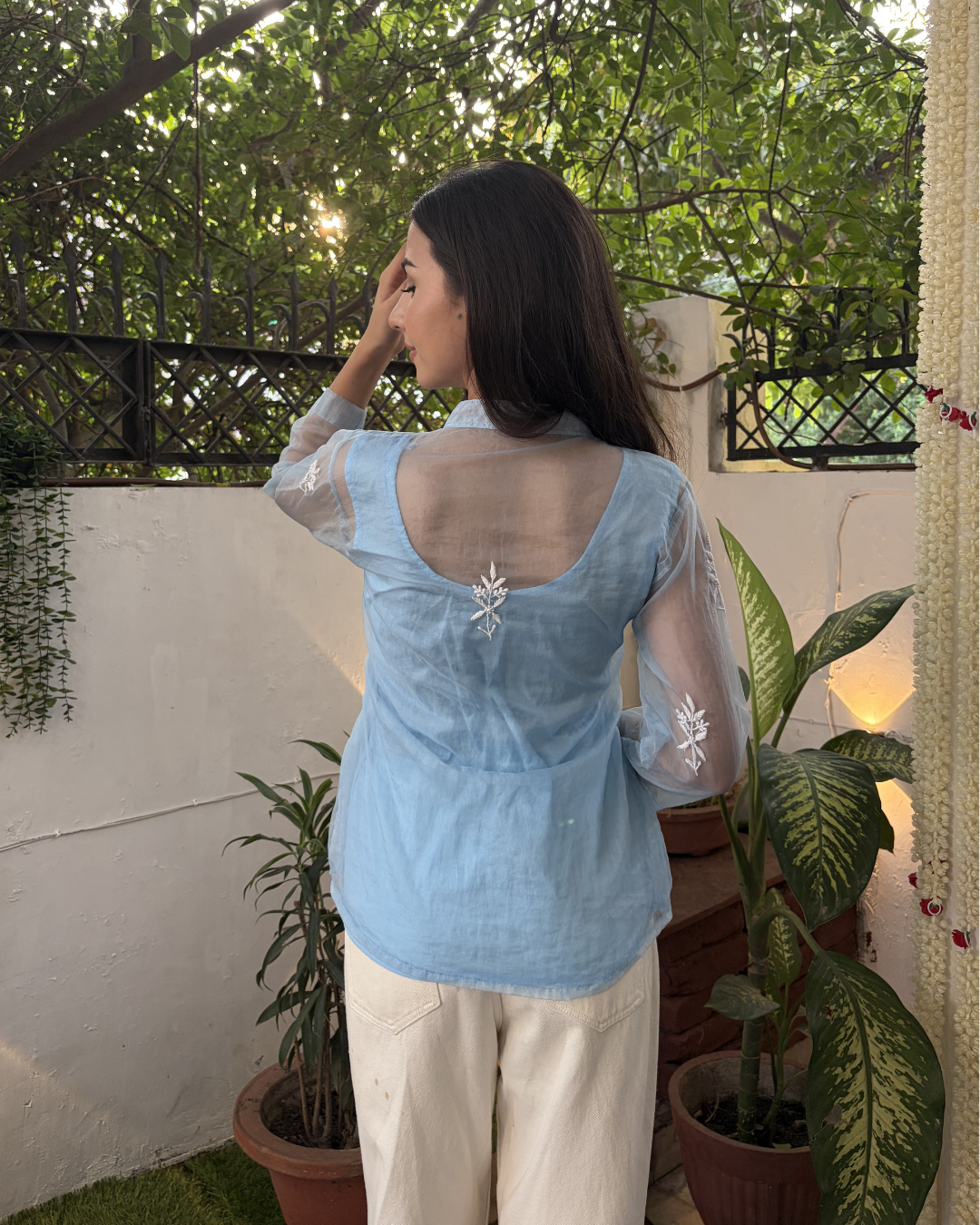 Woman wearing a light blue blouse with a floral pattern in an outdoor setting.