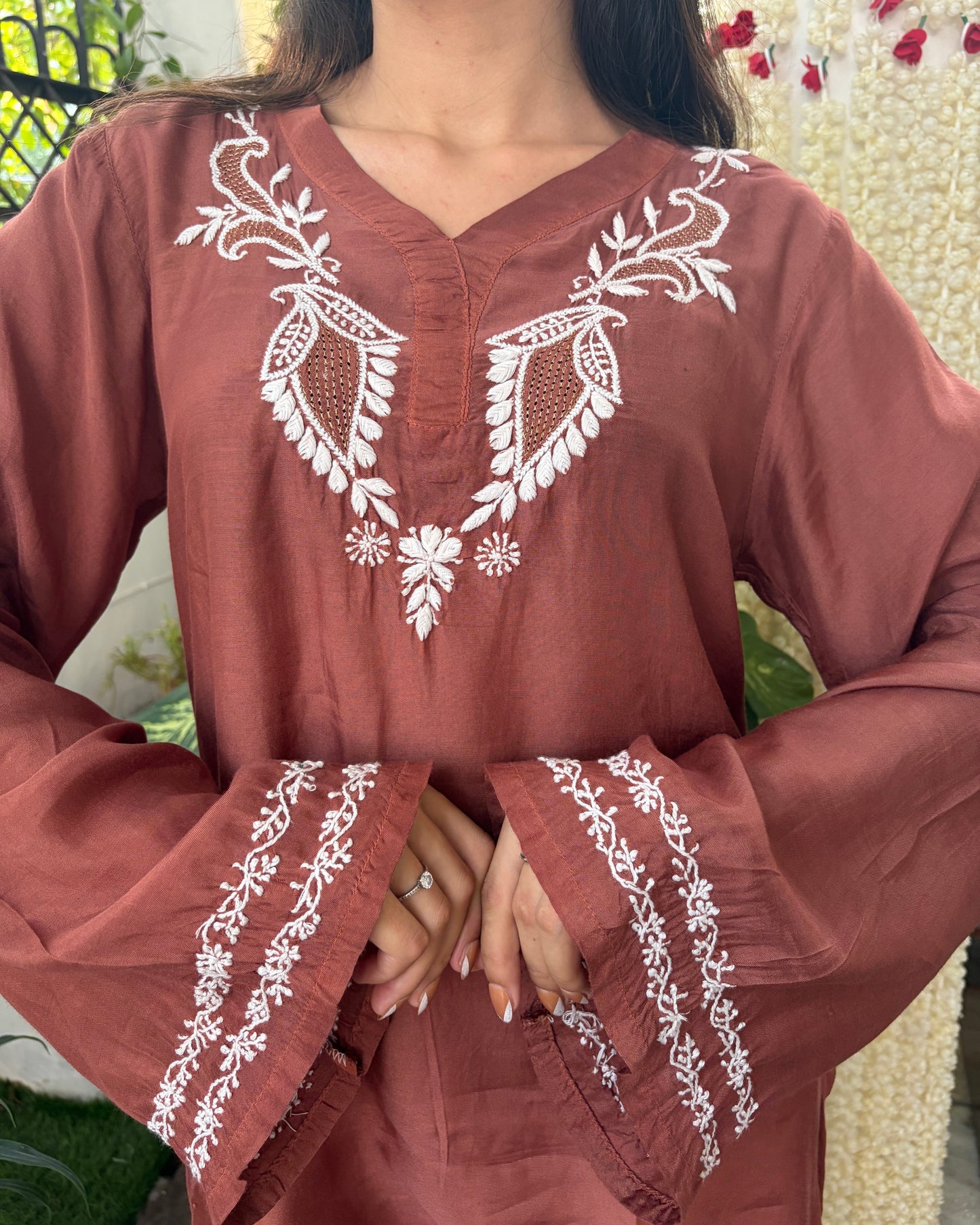 Brown outfit with white embroidery worn by a person, blurred background