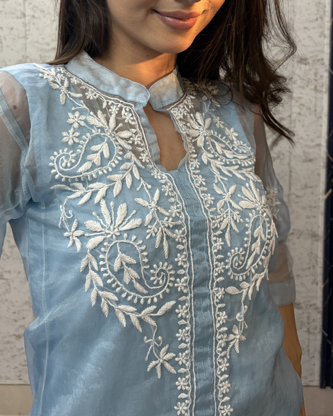 Light blue embroidered top worn by a person against a neutral background